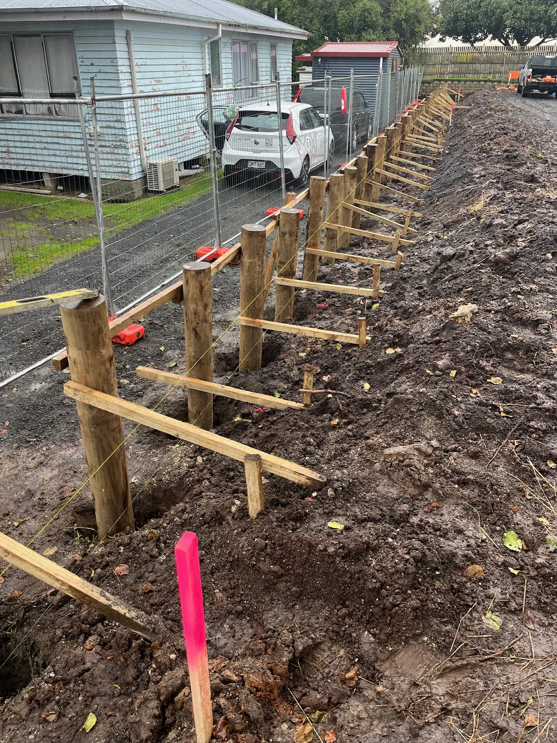 Braced timber retaining wall posts set into an excavated bank in Hamilton
